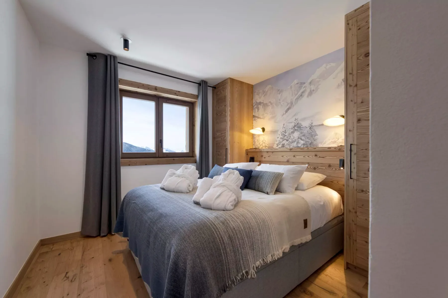 Un dormitorio con una cama grande bajo un mural de montaña.