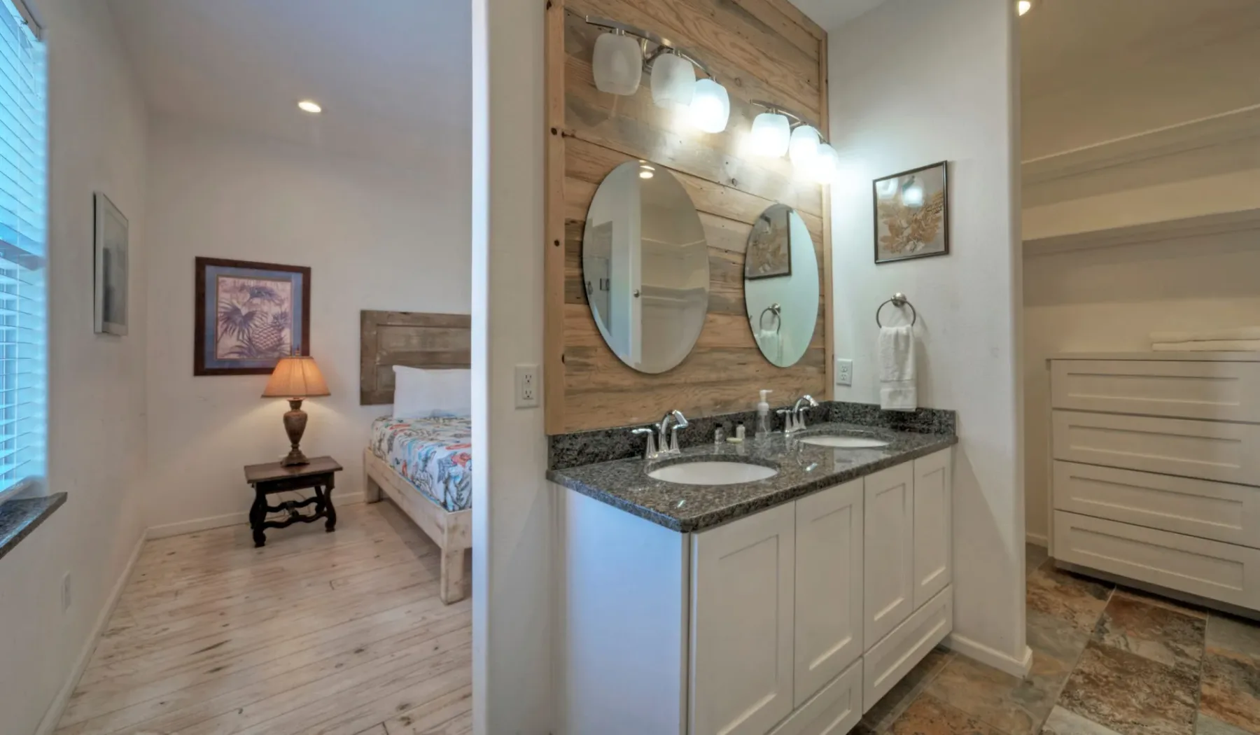 Un tocador de baño con dos espejos da a un dormitorio.