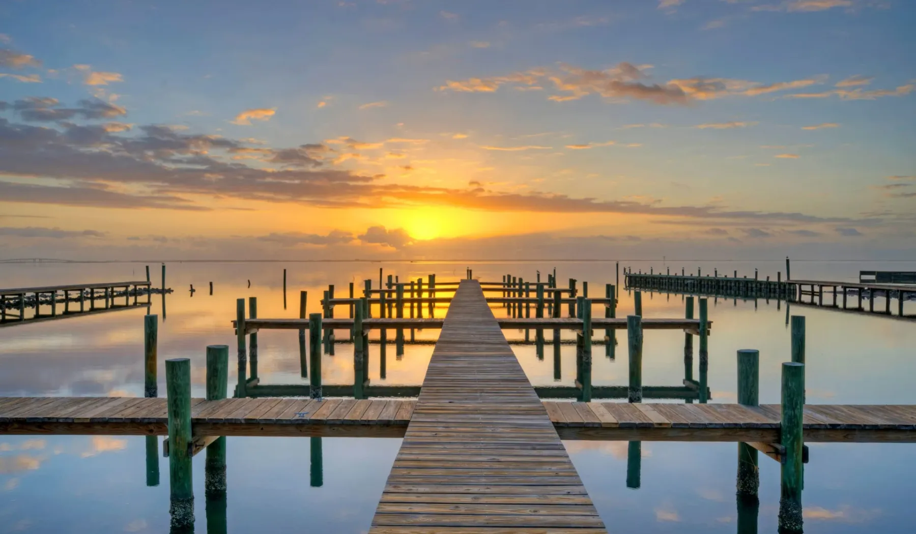 Un muelle de madera se adentra en aguas tranquilas hacia el atardecer.