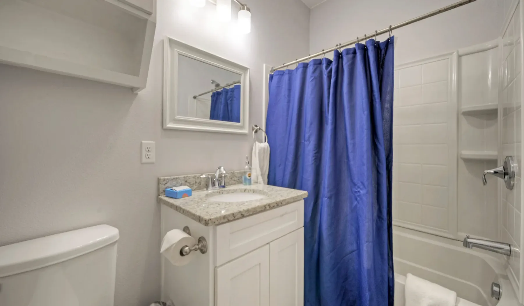 Un baño con un lavabo con mueble y una cortina de ducha azul.