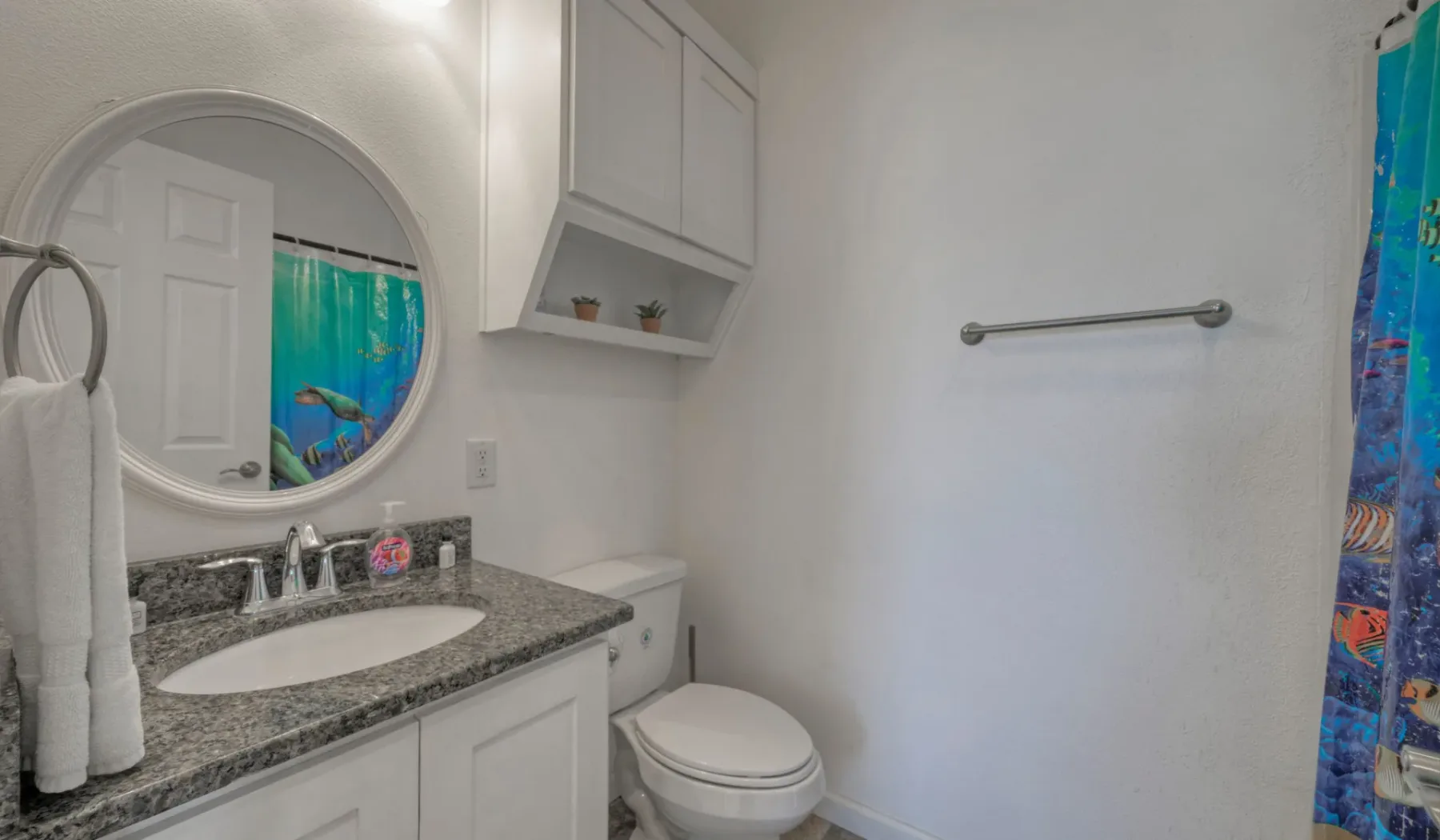 Un baño con lavabo, inodoro y una cortina de ducha colorida.