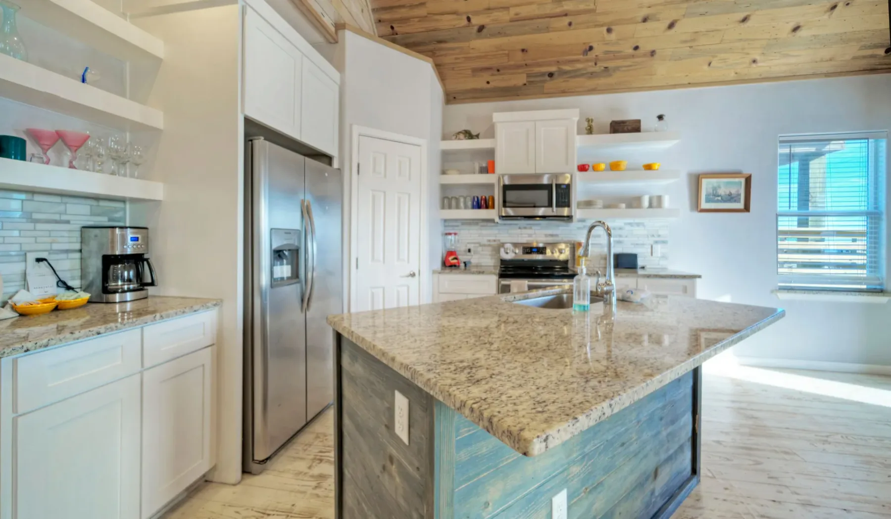 Una cocina luminosa cuenta con una gran isla central y electrodomésticos de acero inoxidable.