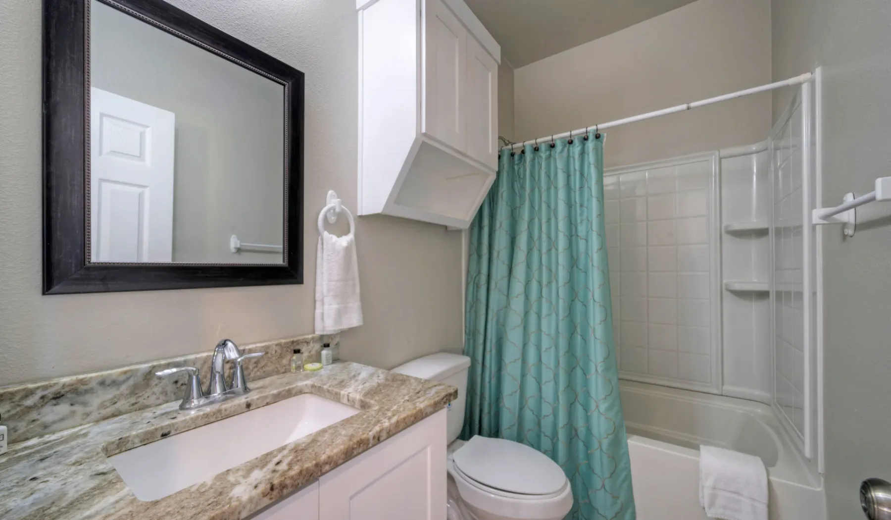 Un baño con lavabo, espejo y bañera con cortina.