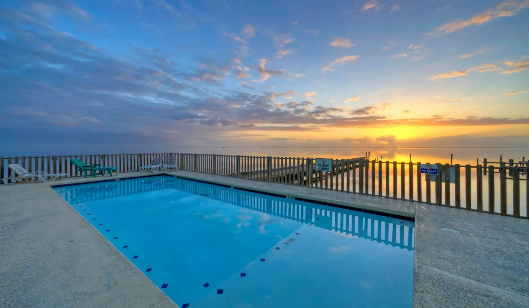 Una piscina al aire libre da al agua al atardecer.