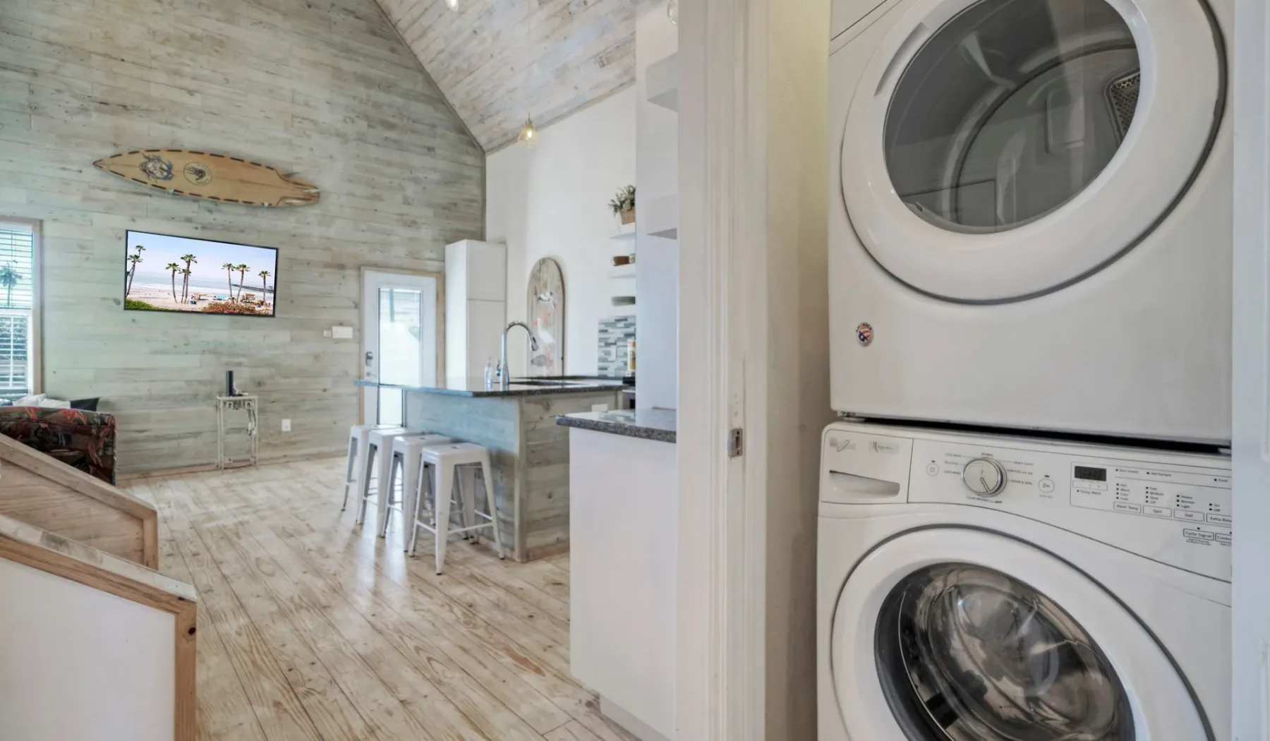 Una cocina abierta y luminosa junto a una sala de estar, con electrodomésticos apilados al frente.