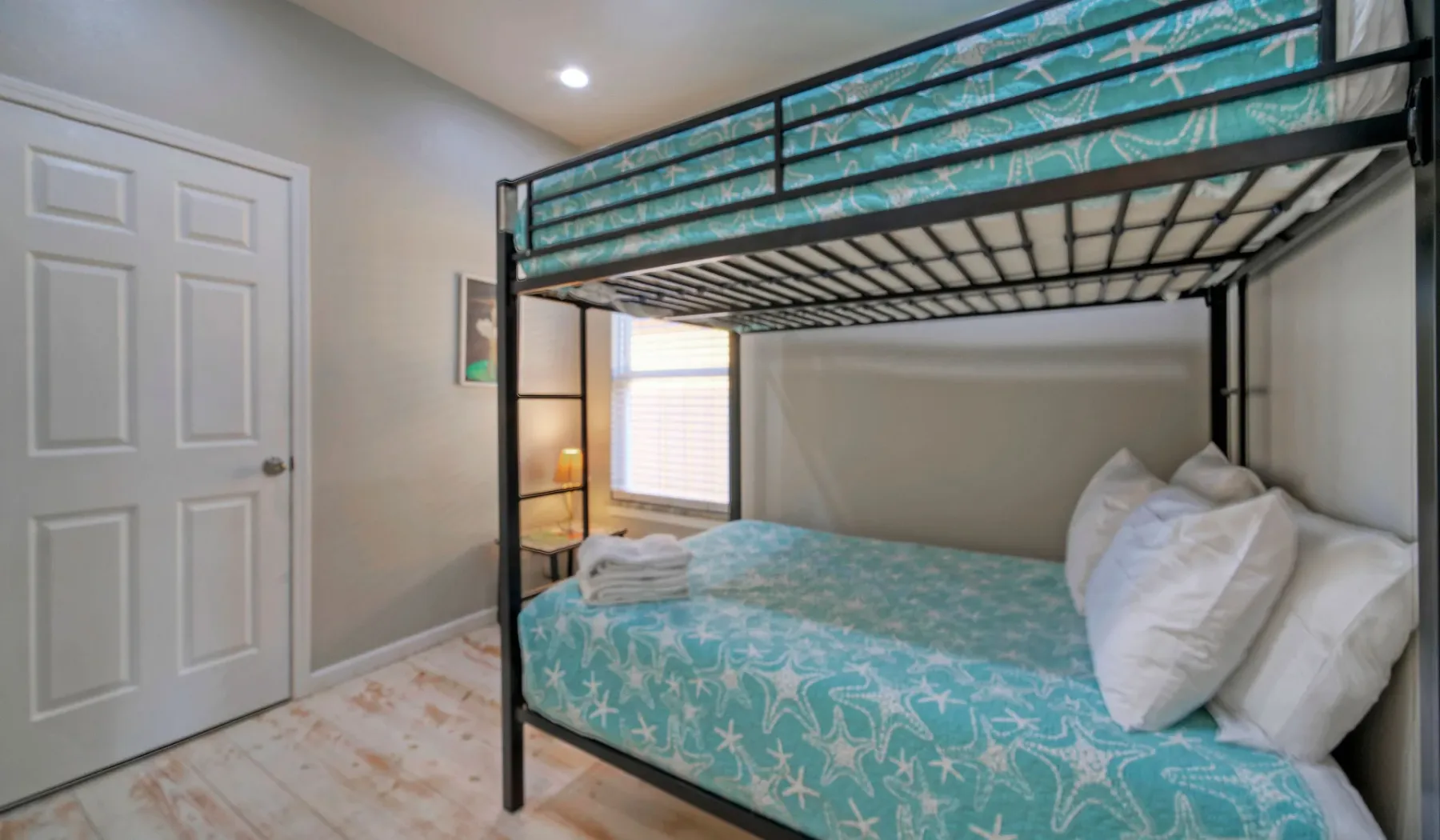 Un dormitorio con una litera vestida con ropa de cama turquesa estampada.