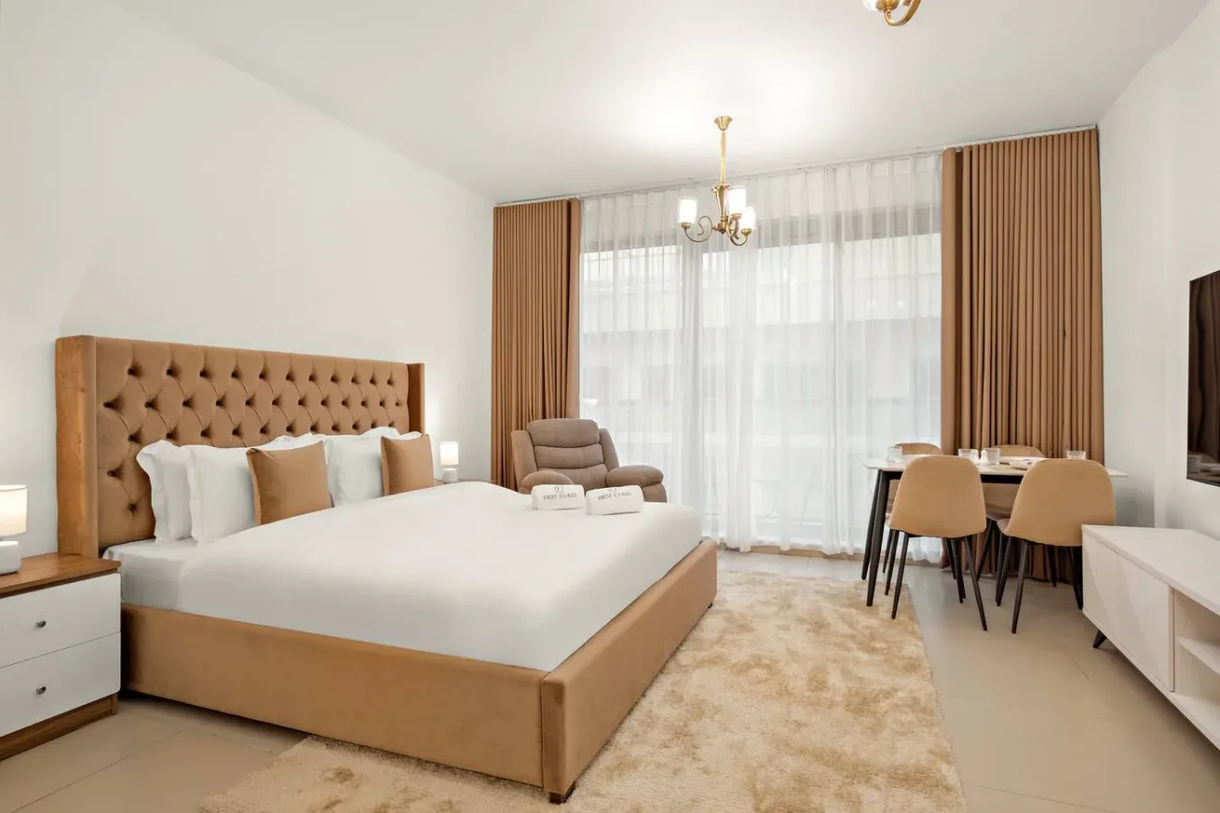 Un dormitorio luminoso con una cama grande, asientos y una mesa junto a la ventana.