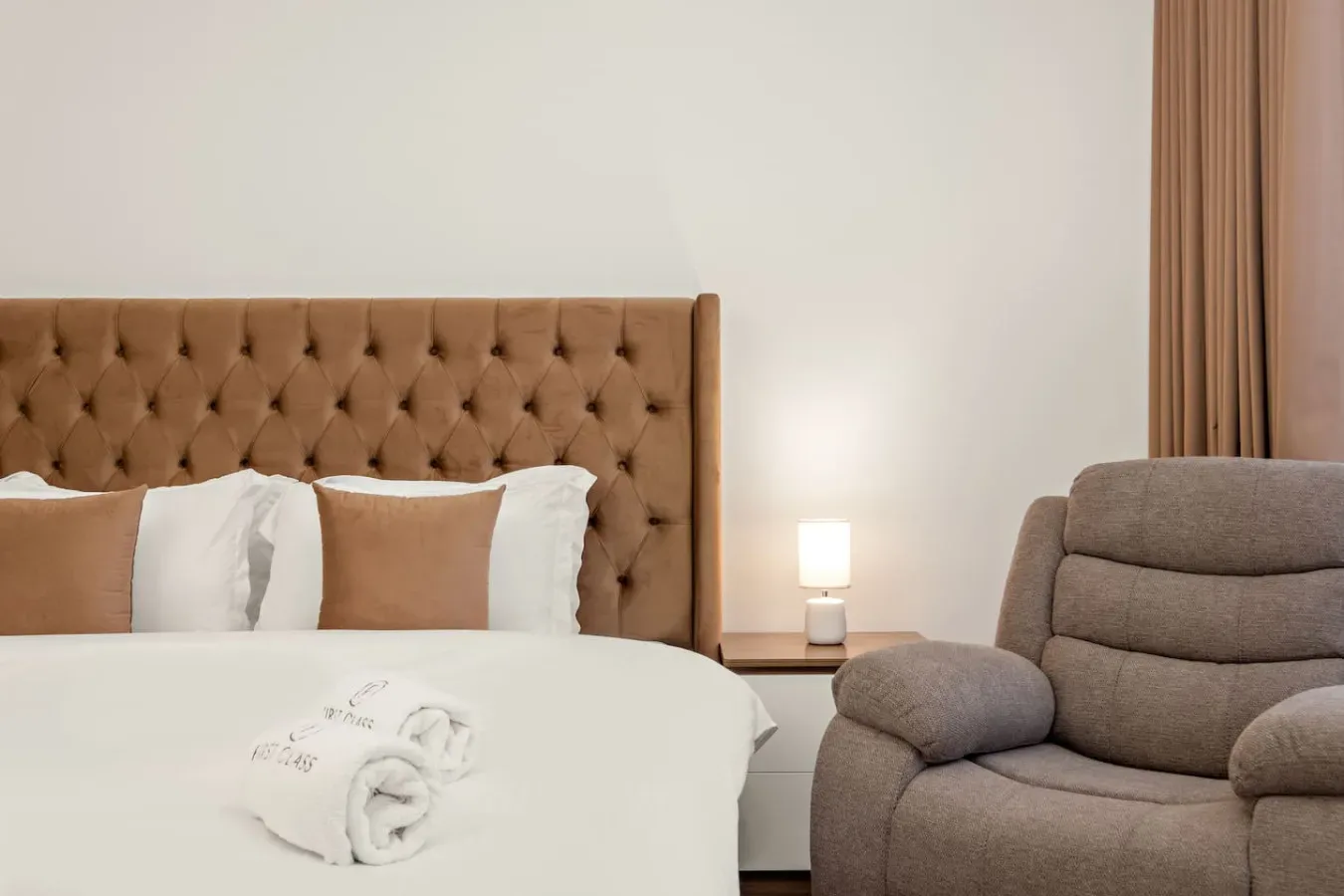Un dormitorio con una cama junto a un sillón acolchado.