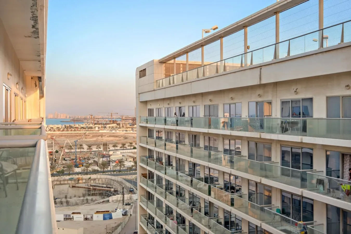Vista entre edificios modernos hacia una zona de construcción junto al agua.