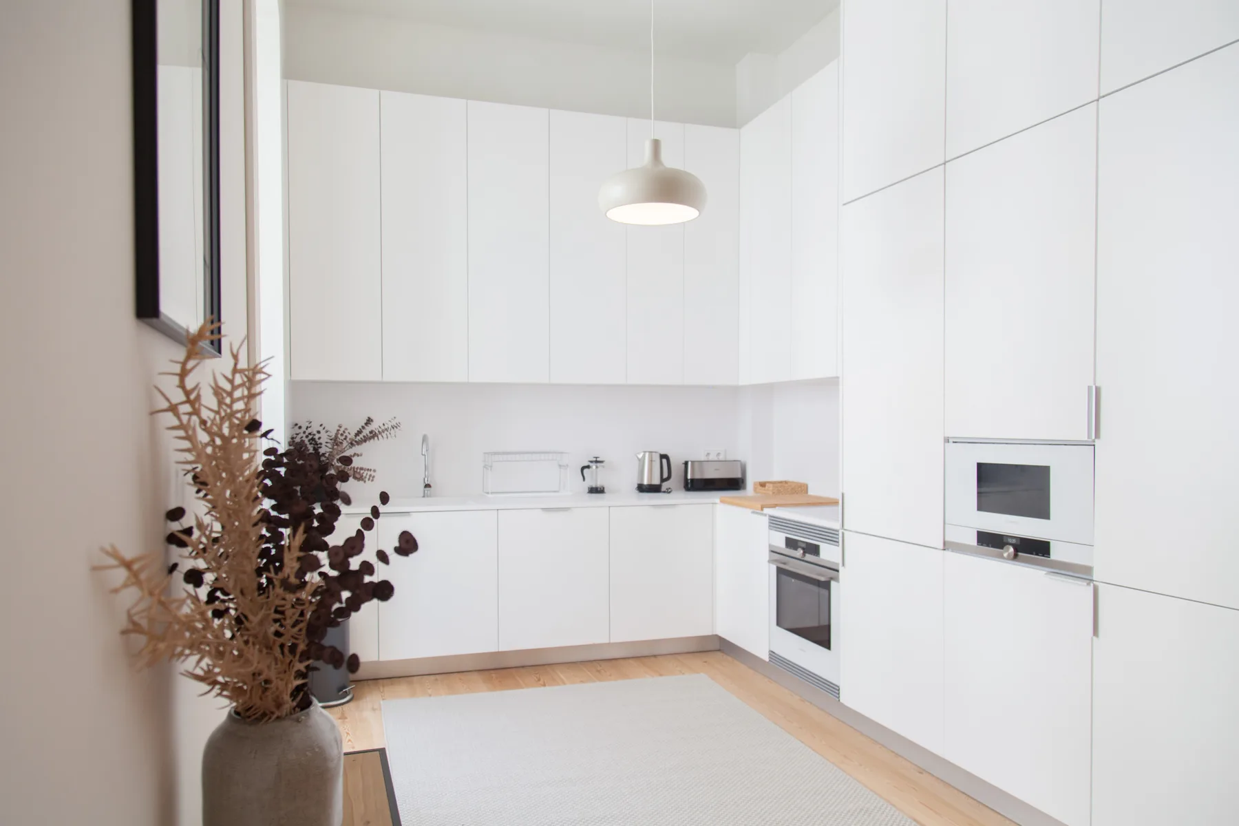 Una cocina moderna y luminosa con armarios blancos y una zona de trabajo central.