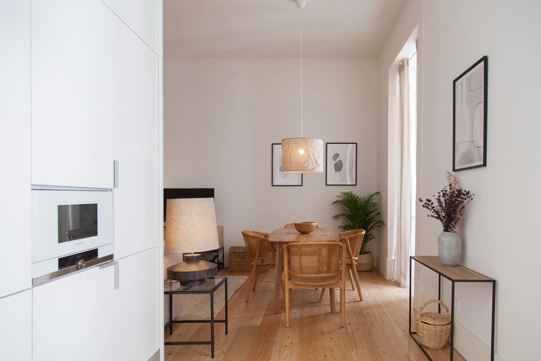 Comedor luminoso con mesa y sillas de madera junto a una cocina compacta.