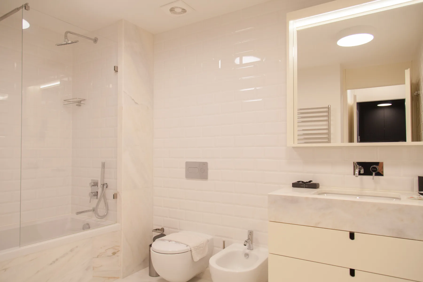 Un baño luminoso con azulejos, ducha, lavabo, inodoro y bidé.