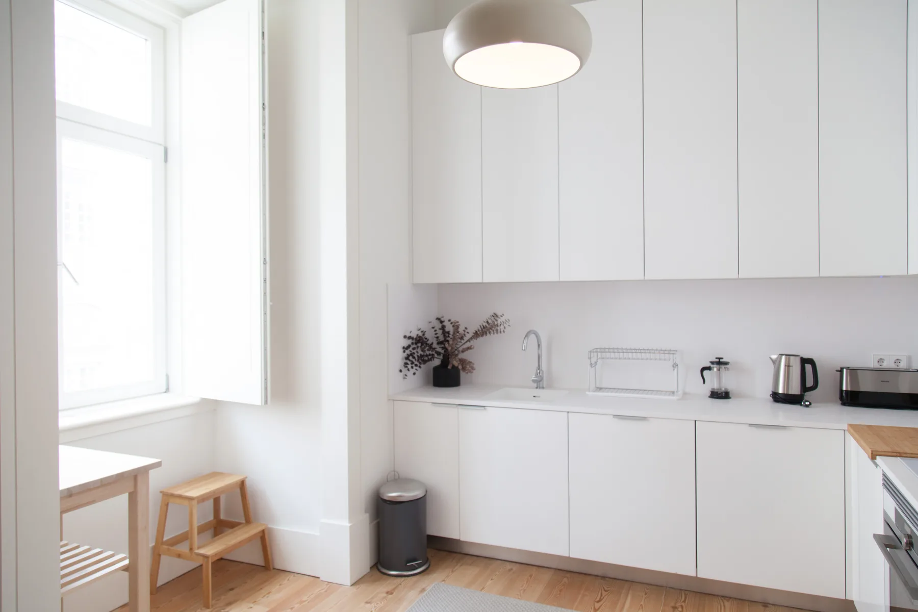 Una cocina blanca y luminosa con encimera, fregadero y una ventana grande.