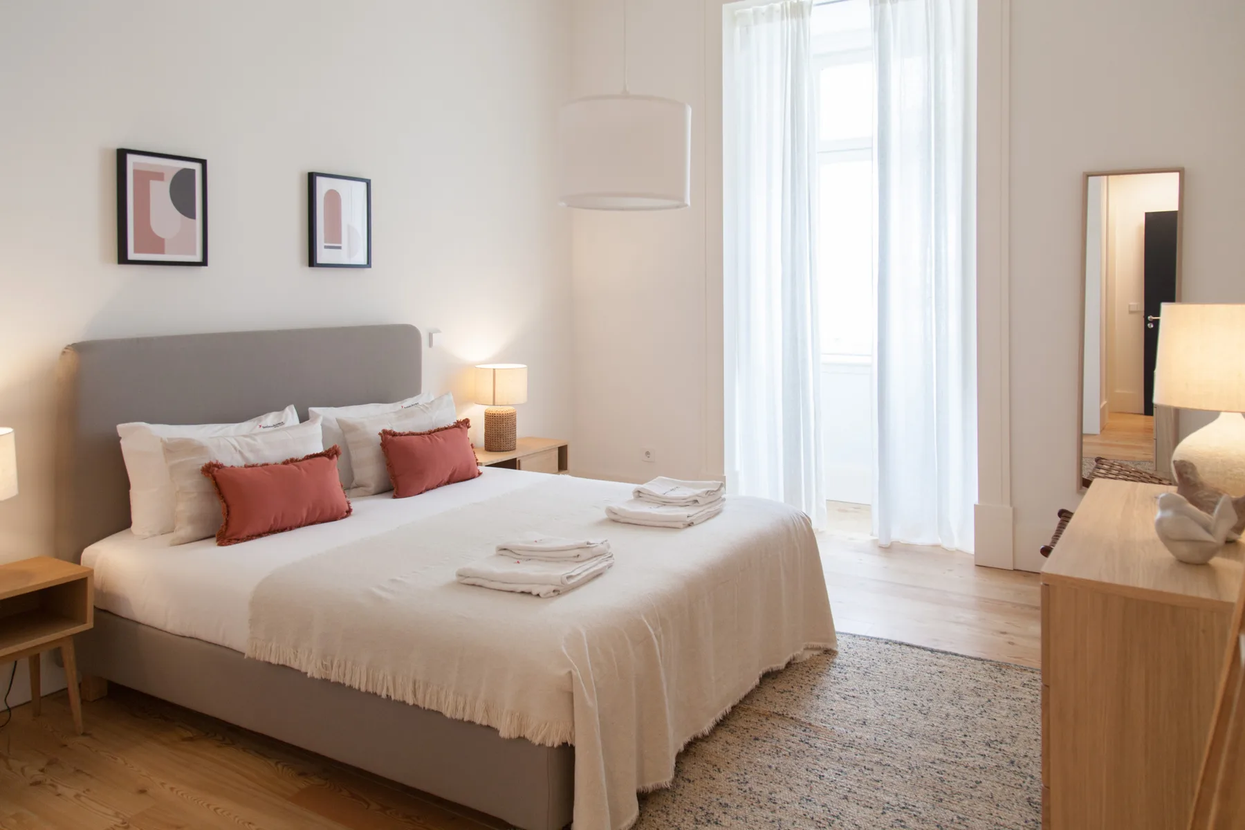 Un dormitorio luminoso con una cama bien tendida y una ventana alta.