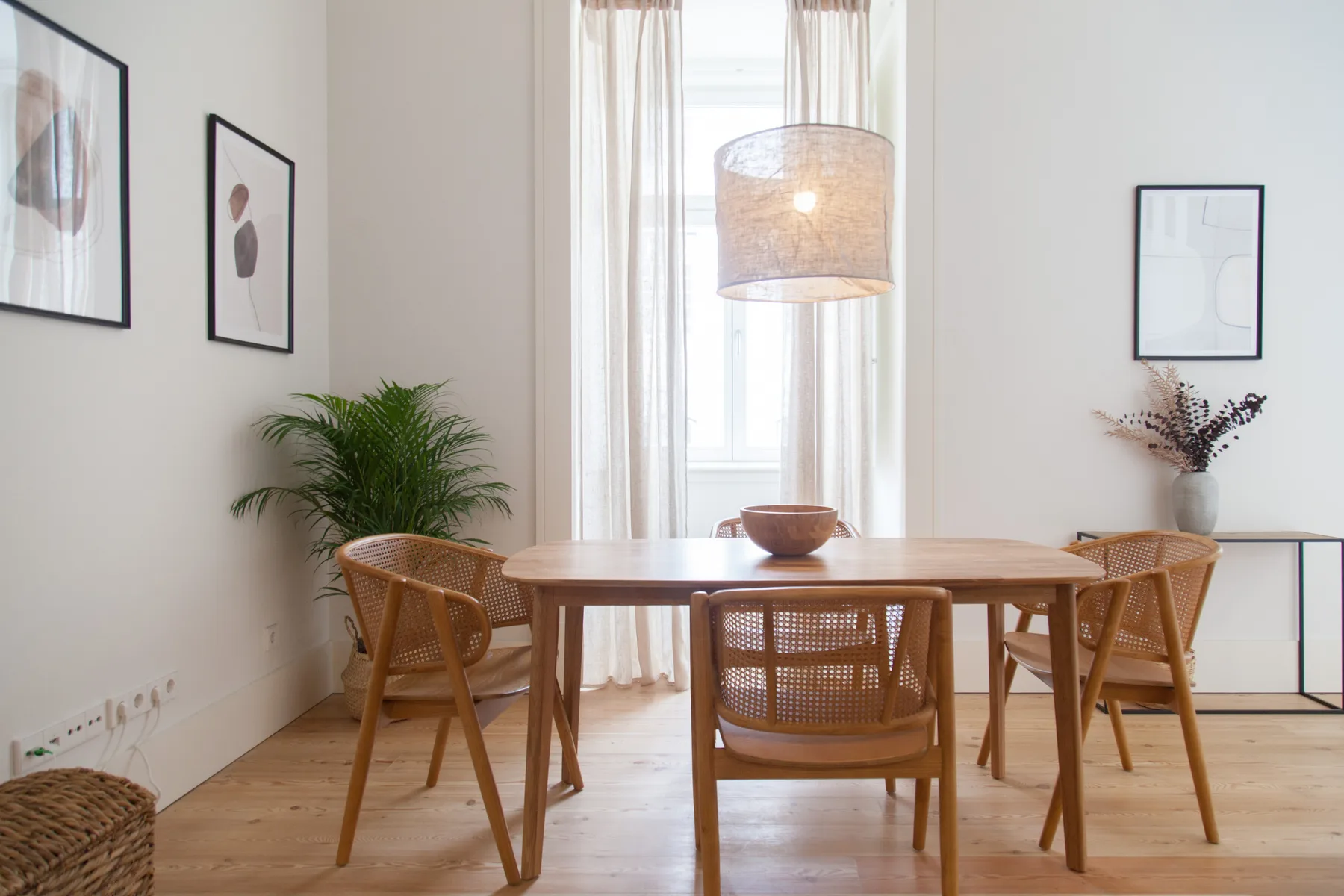 Un comedor luminoso con una mesa de madera y asientos de rejilla.