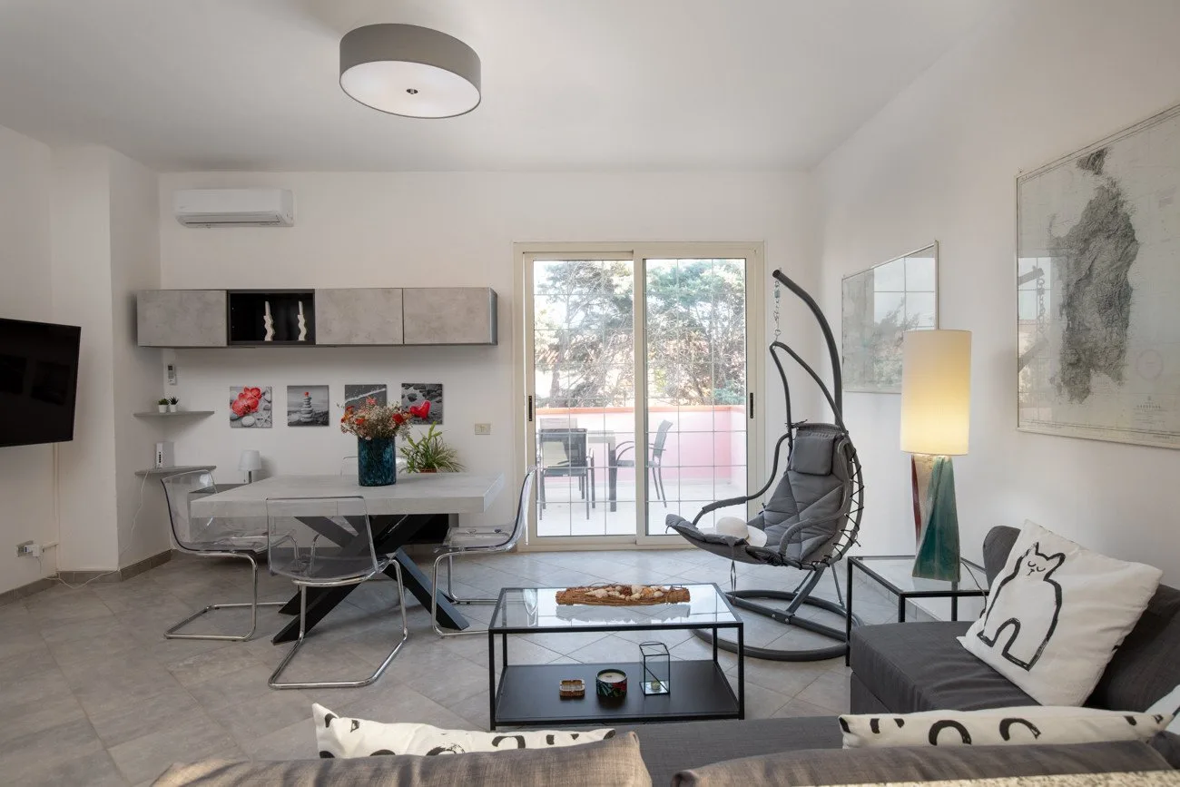 A bright living room with seating, a glass coffee table, and sliding glass doors.
