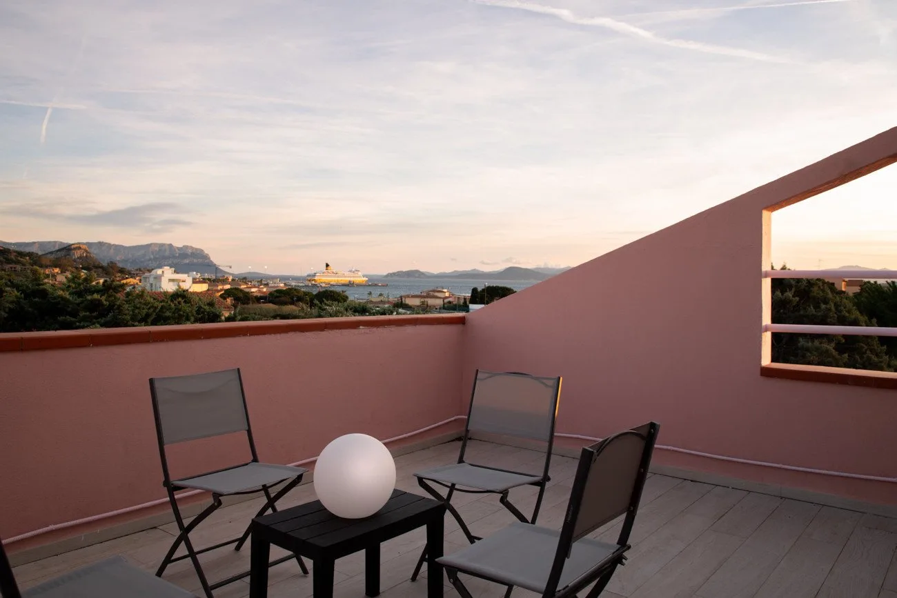 Una terraza en la azotea con asientos al aire libre da a colinas lejanas y al agua.