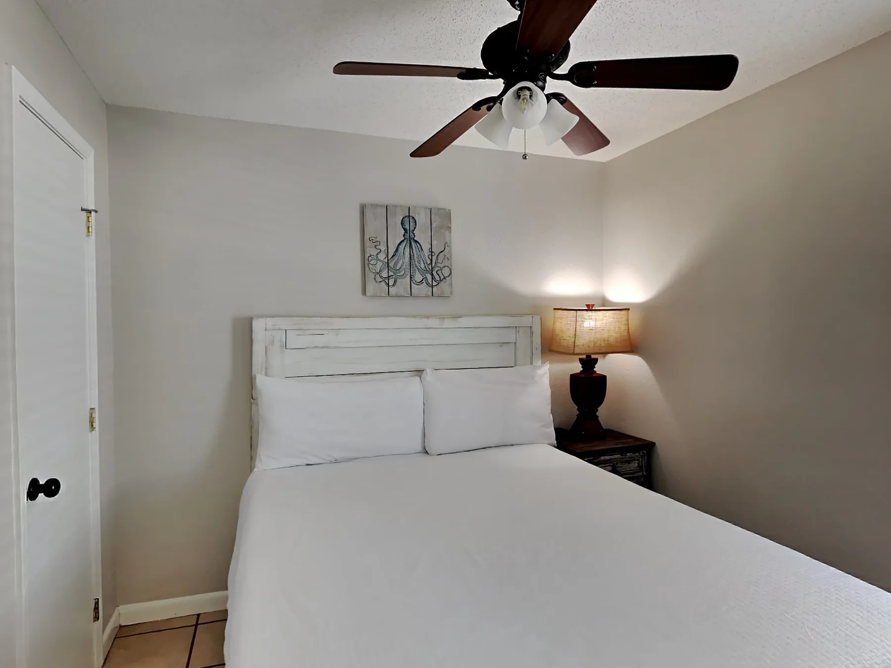 Dormitorio con una cama blanca y una lámpara de noche encendida.