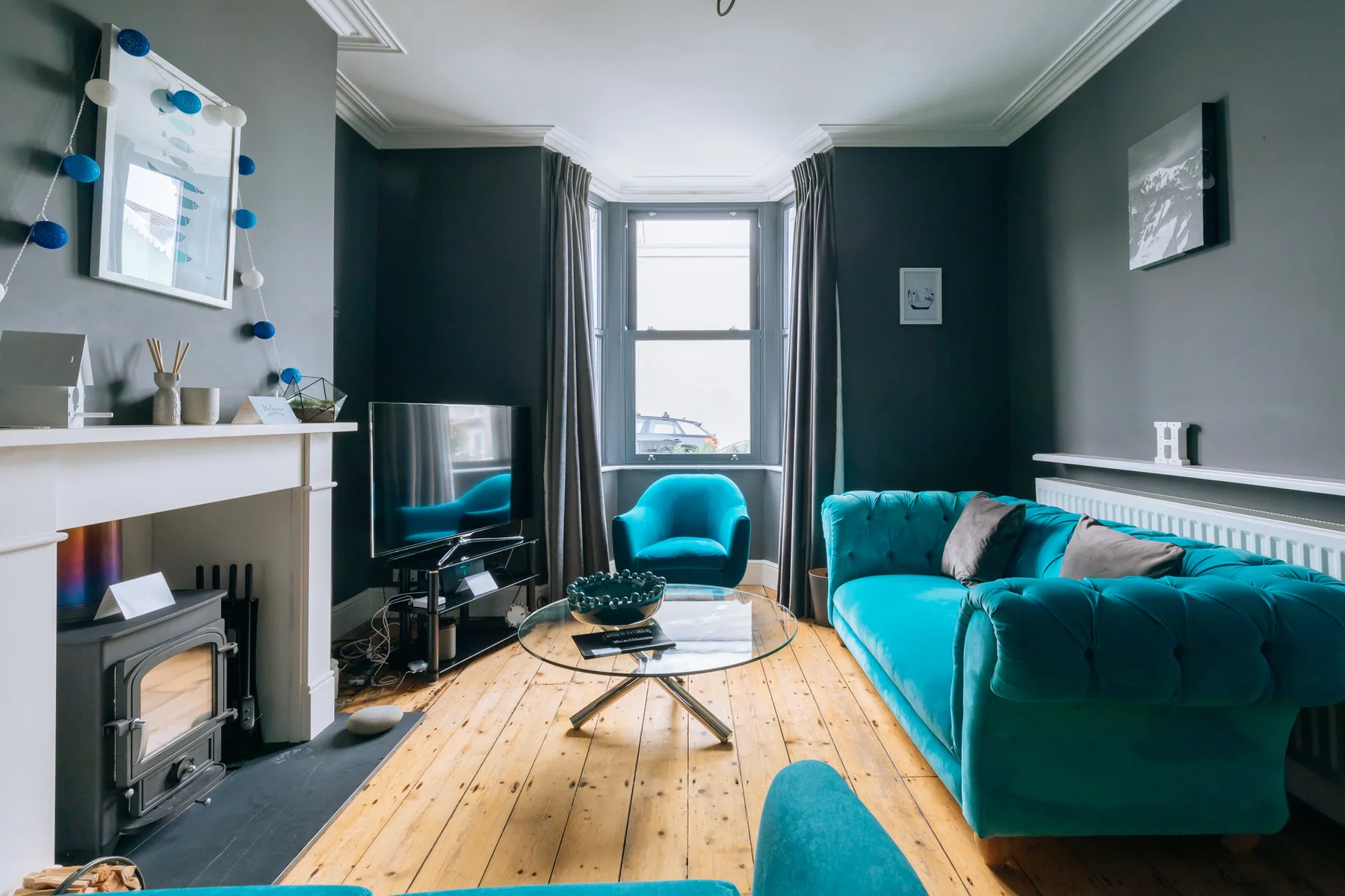 A living room with teal seating, a coffee table, and a fireplace.