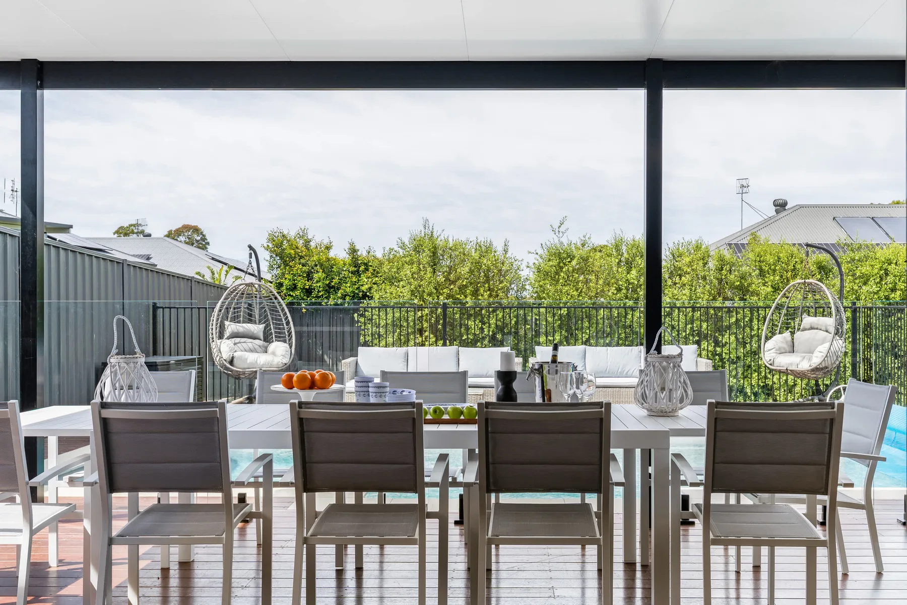Una zona de comedor al aire libre con mesa, asientos y sillas colgantes.