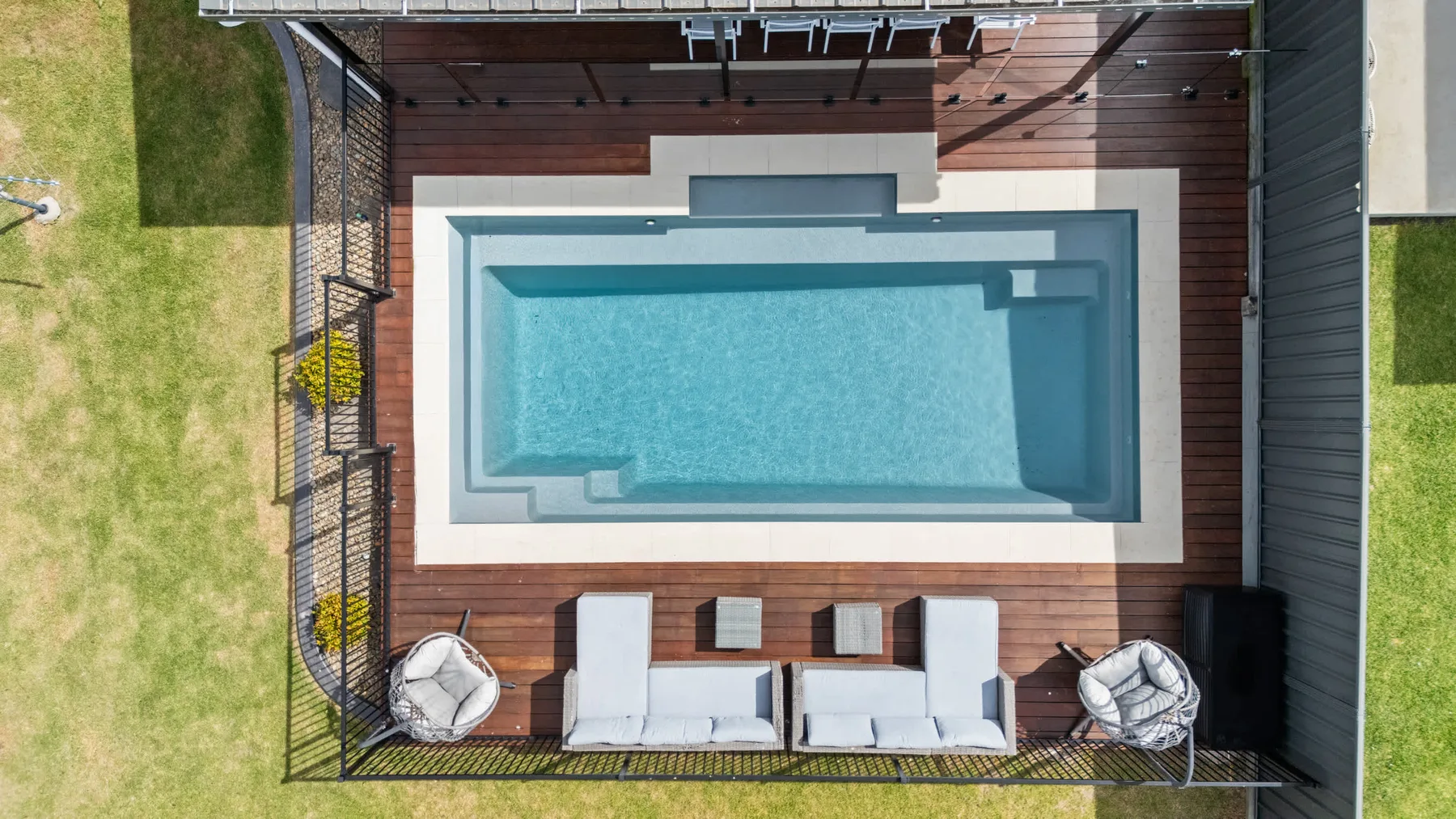 Una piscina al aire libre está junto a una terraza de madera y asientos.
