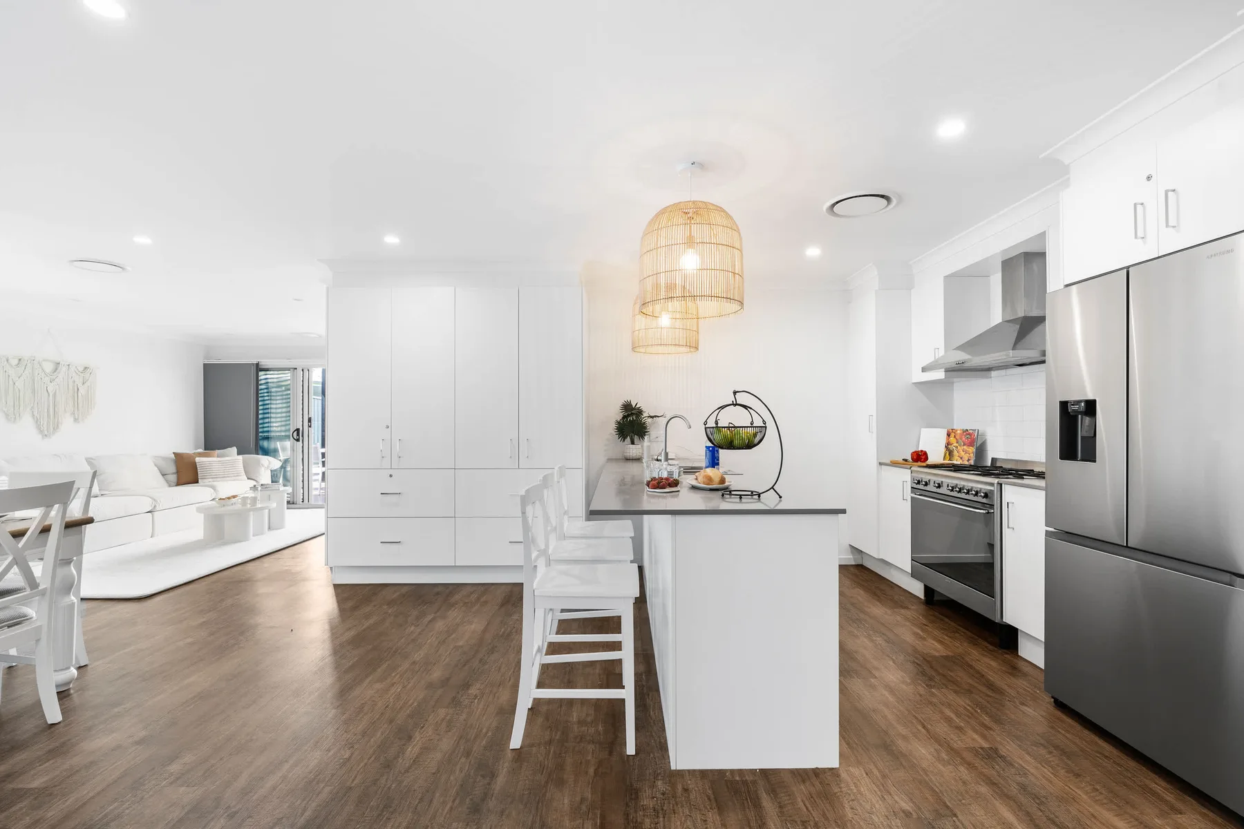 Cocina y sala de estar de concepto abierto con una isla central y asientos blancos.