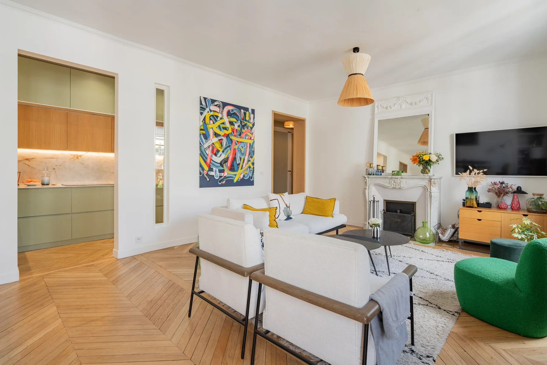 A bright living room with white seating, colorful artwork, and a fireplace.