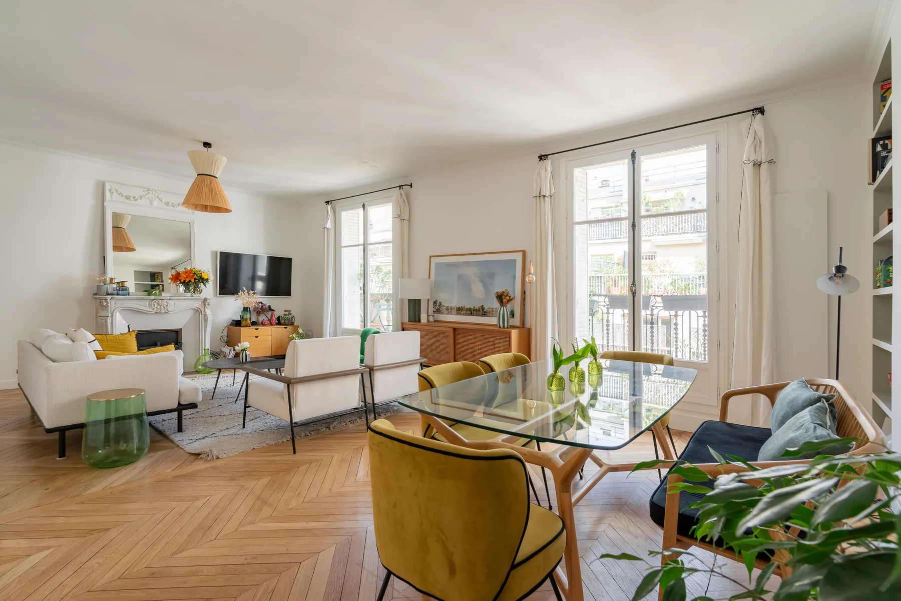A bright living room with seating around a glass dining table and large windows.