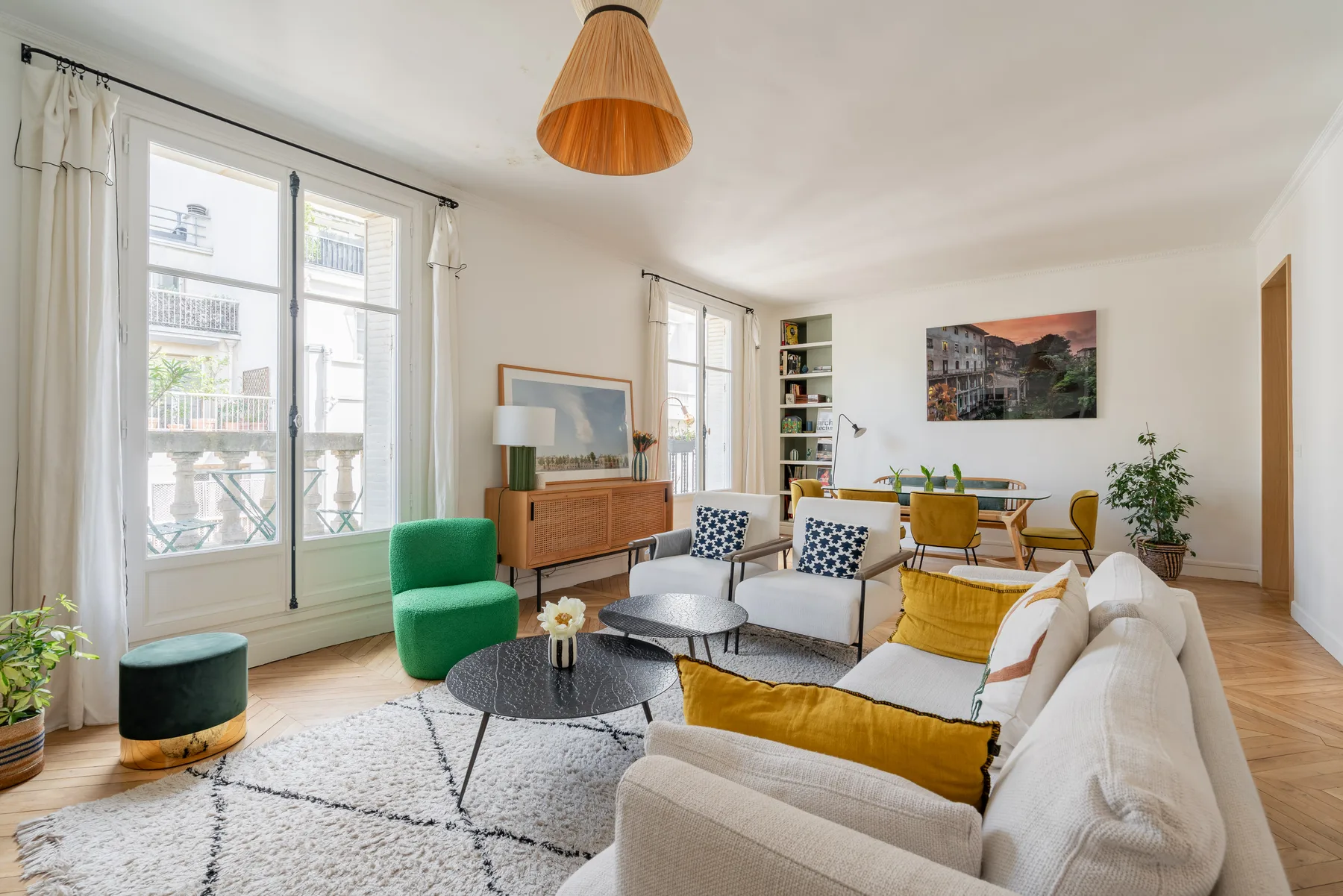 A bright living room with seating around a coffee table and a dining area beyond.