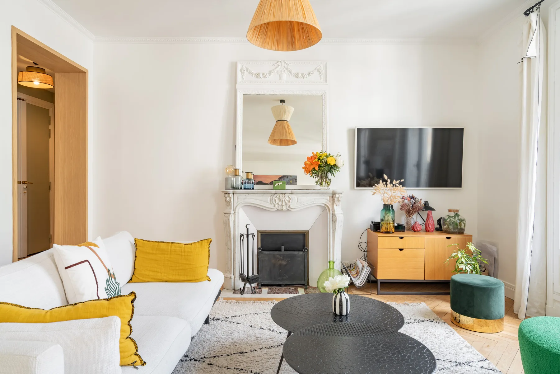Una sala luminosa con asientos blancos, una chimenea y un televisor.