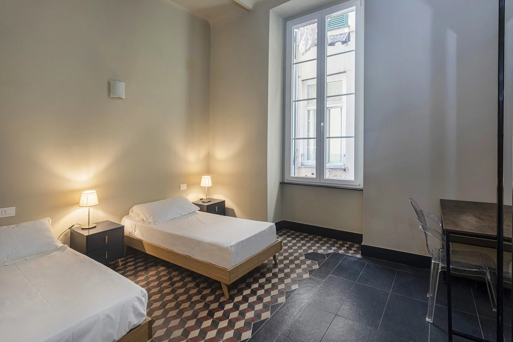 A bedroom with two single beds beside a tall window.