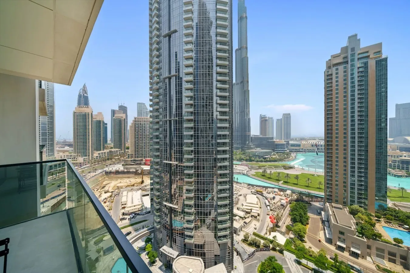 A balcony overlooks tall city buildings, roads, and a turquoise waterway.