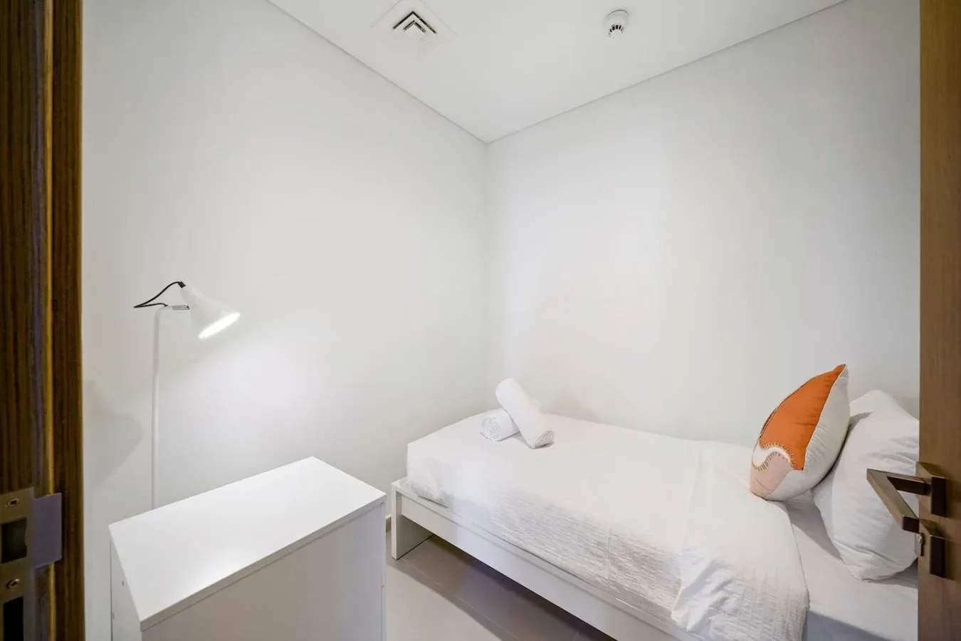 A bright bedroom with a single bed and a white bedside cabinet.