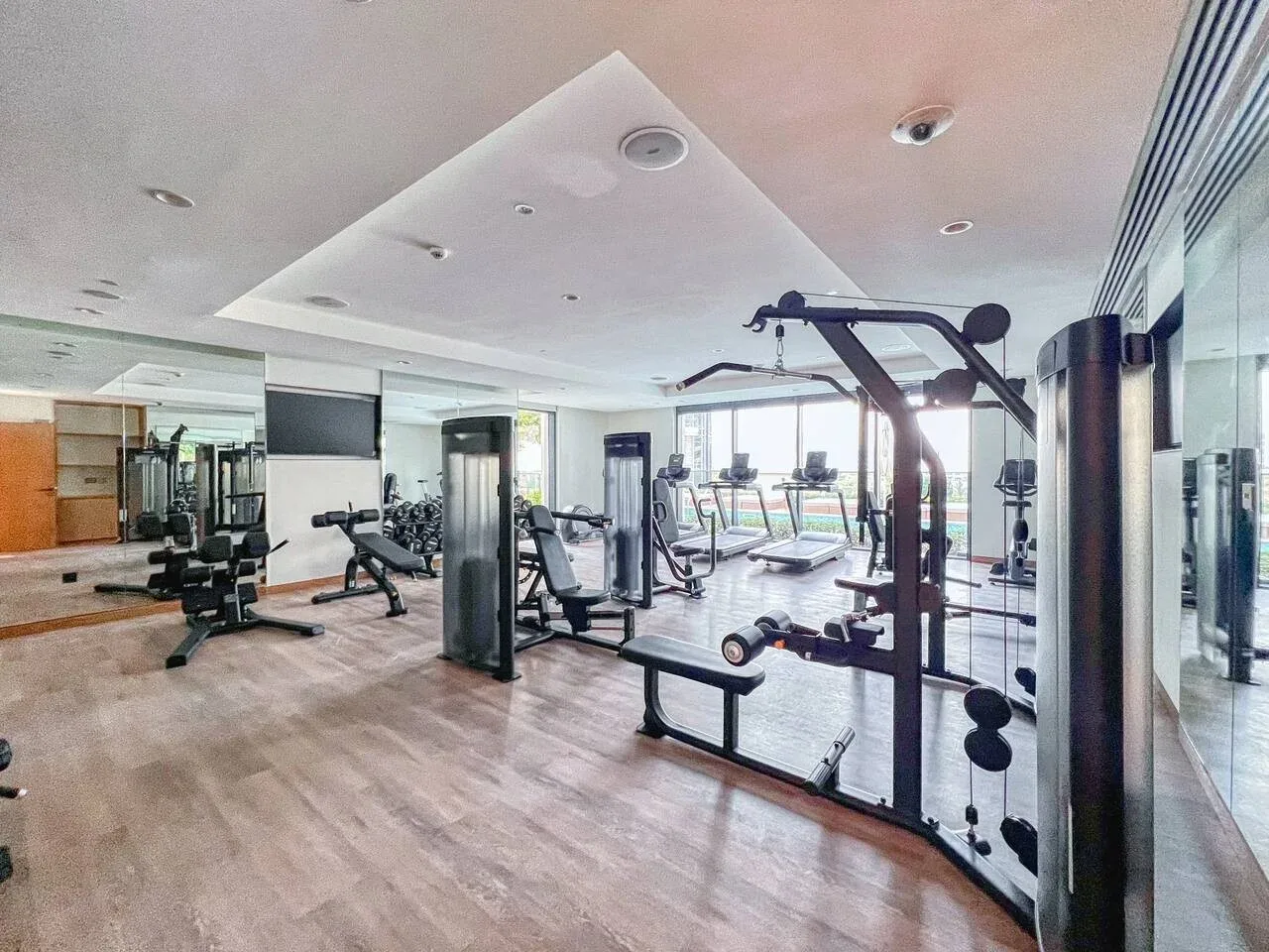 A gym with exercise machines, weights, and mirrored walls.