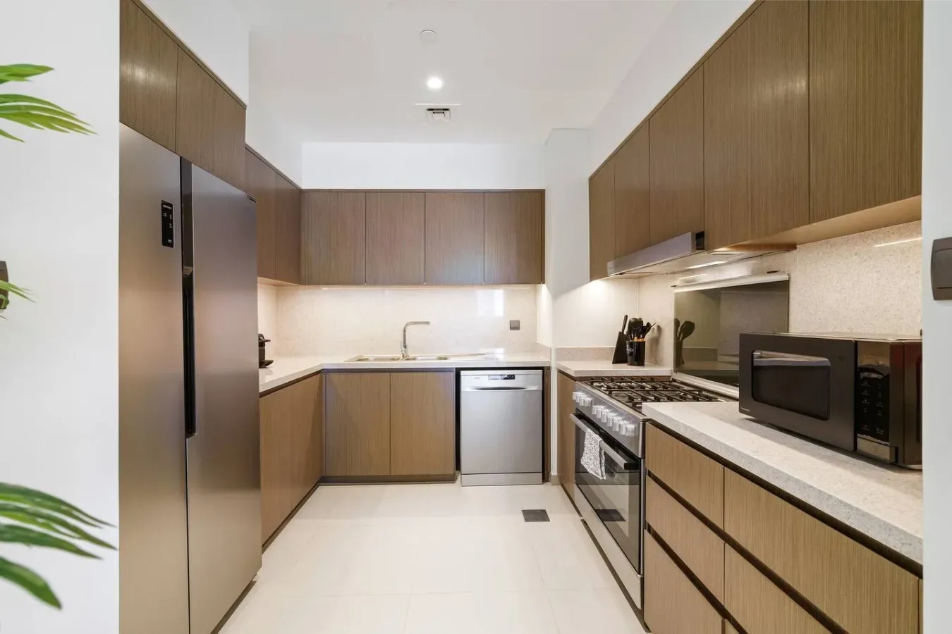 A modern kitchen with wood cabinetry, stainless steel appliances, and light countertops.