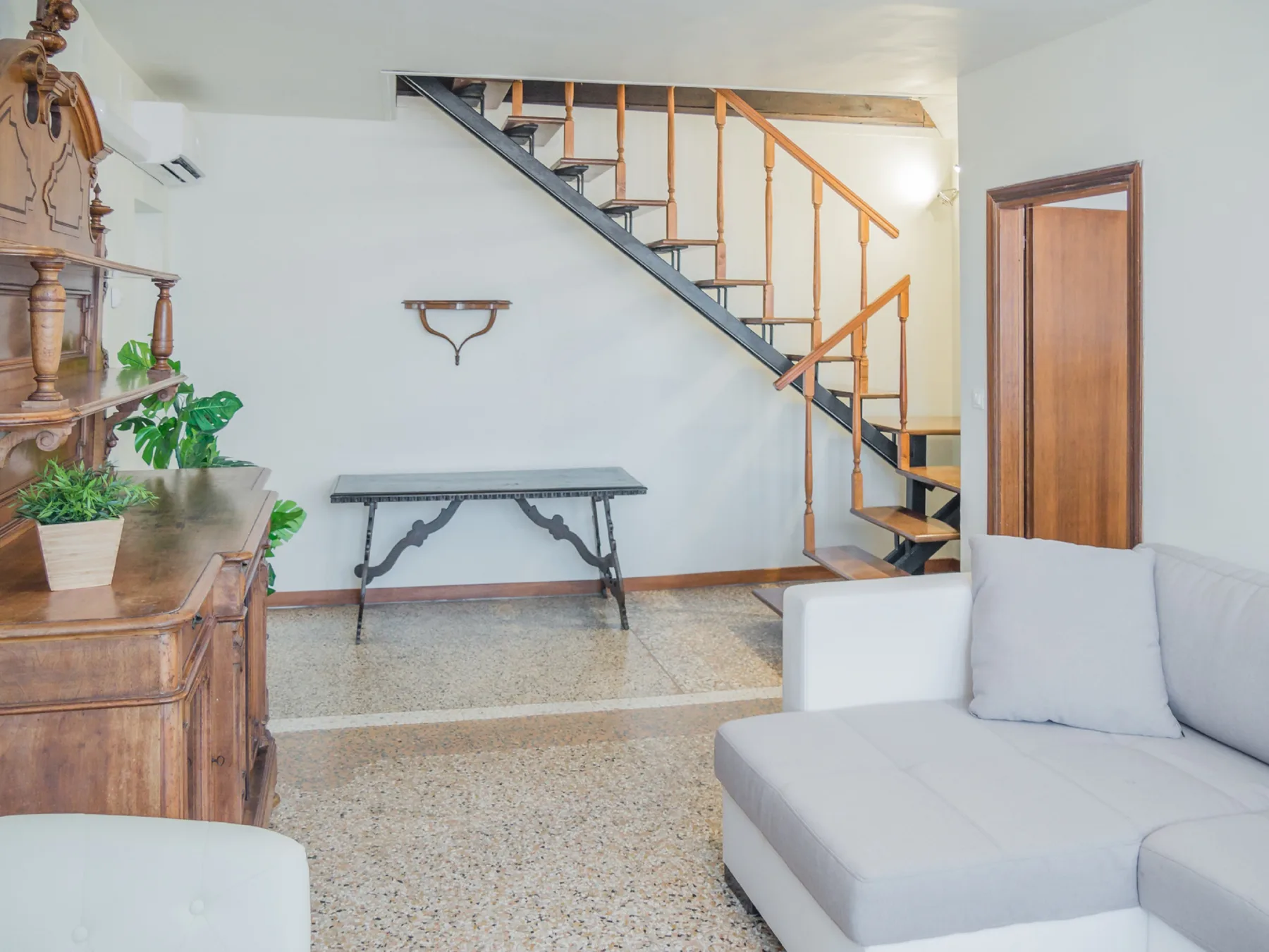 A living room with a staircase and light-colored seating.
