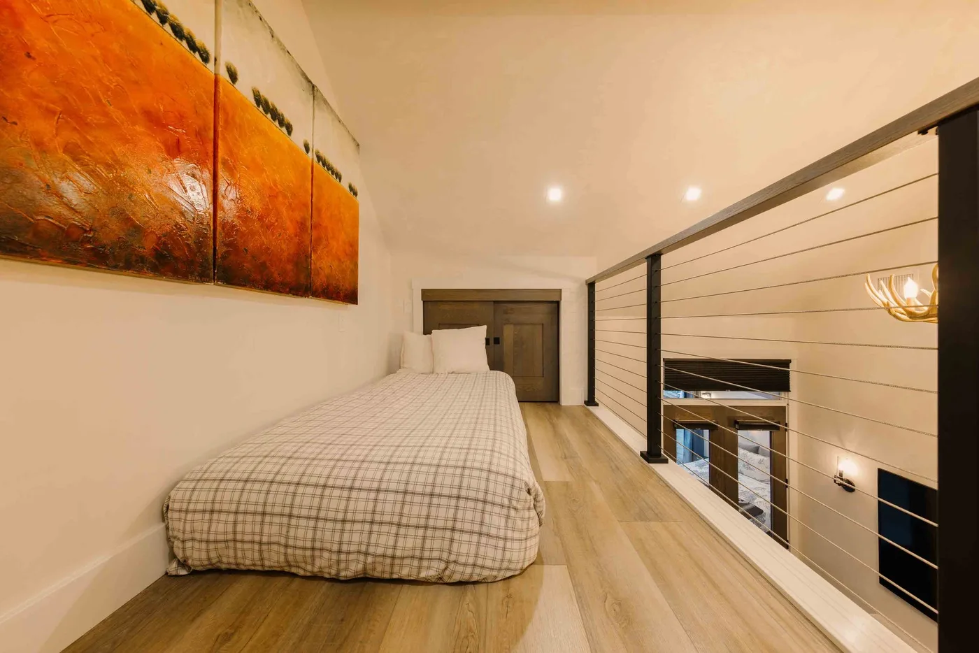 Un dormitorio con una cama junto a una barandilla que da al piso inferior.