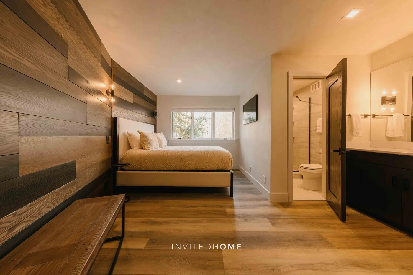 Un dormitorio con una cama bajo una ventana y una puerta abierta hacia el baño.
