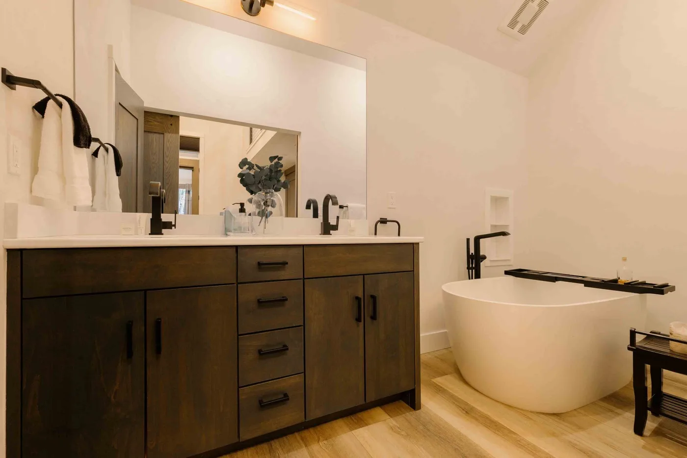 Un baño con un tocador oscuro y una bañera exenta.