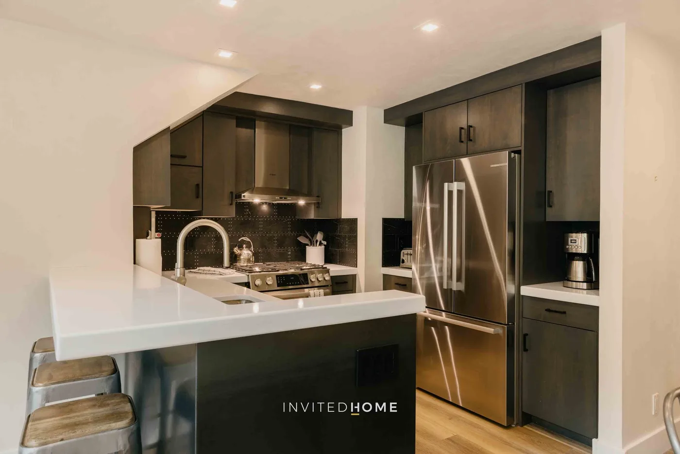 Una cocina moderna con gabinetes oscuros, una isla central y electrodomésticos de acero inoxidable.