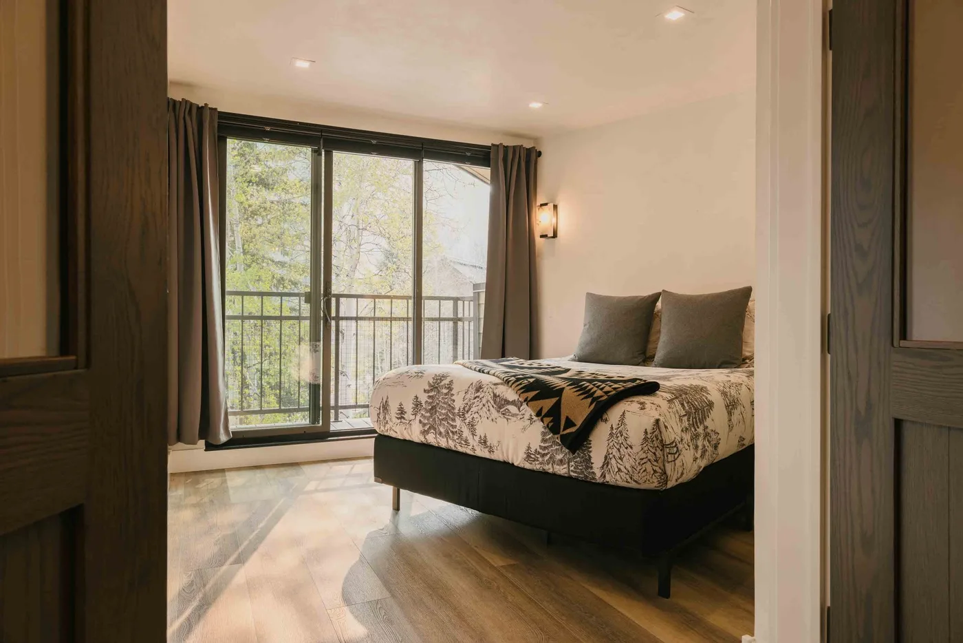 Un dormitorio con una cama junto a puertas de vidrio que dan a un balcón.