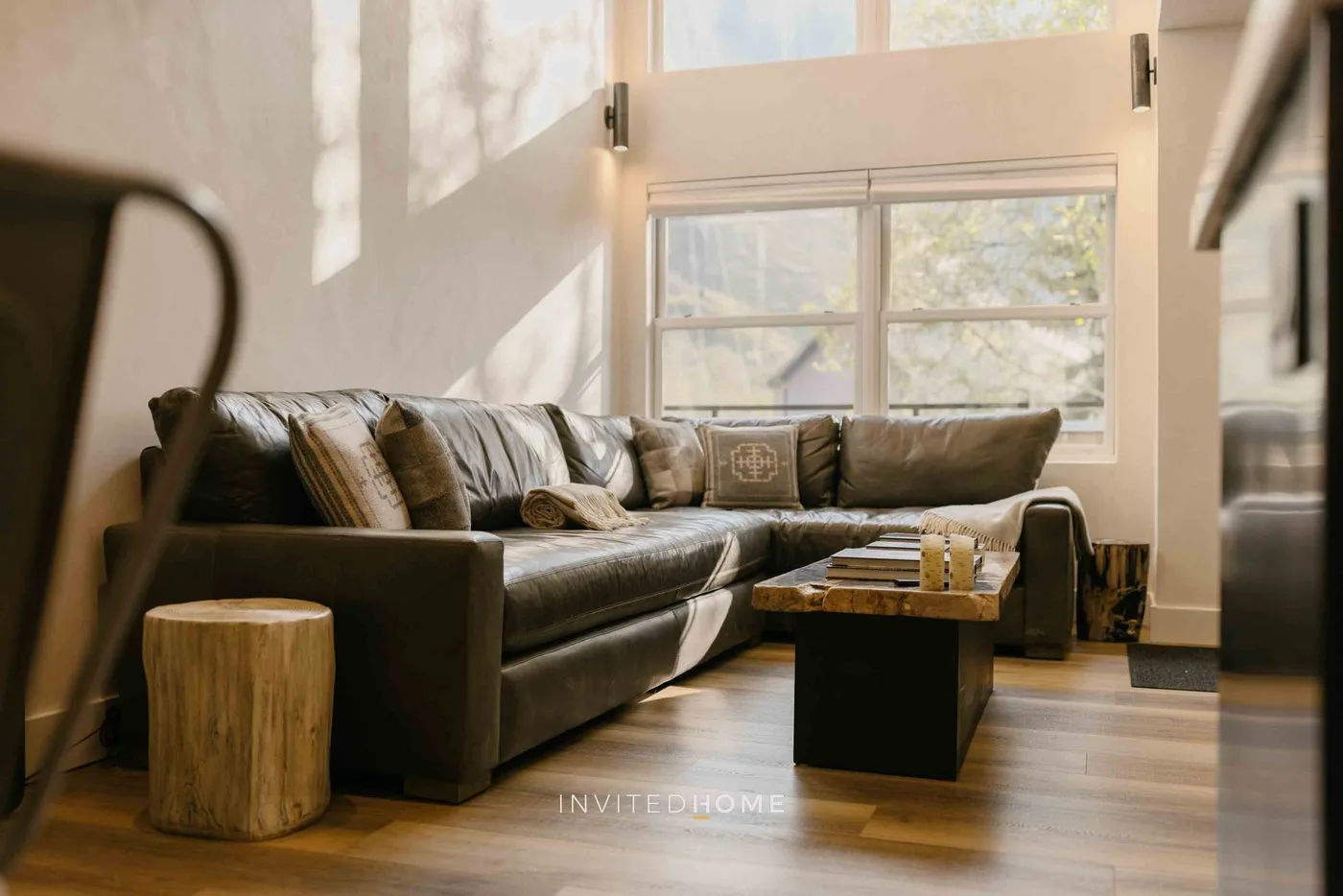 Una sala de estar con un sofá seccional y una mesa baja junto a las ventanas.