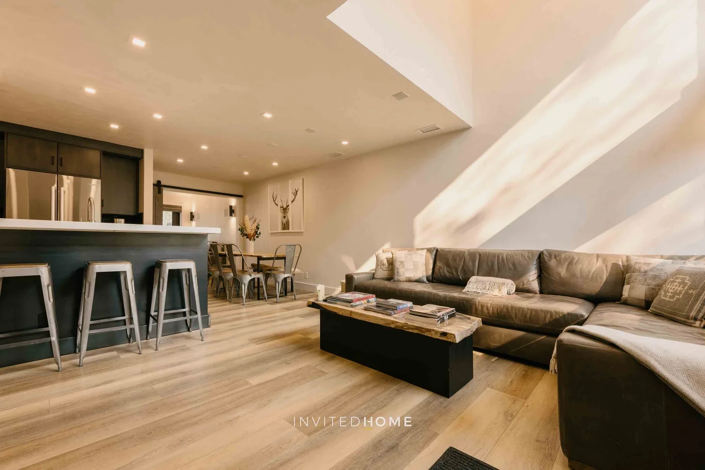 Una sala de estar con sofá seccional, mesa de centro y barra de cocina contigua.