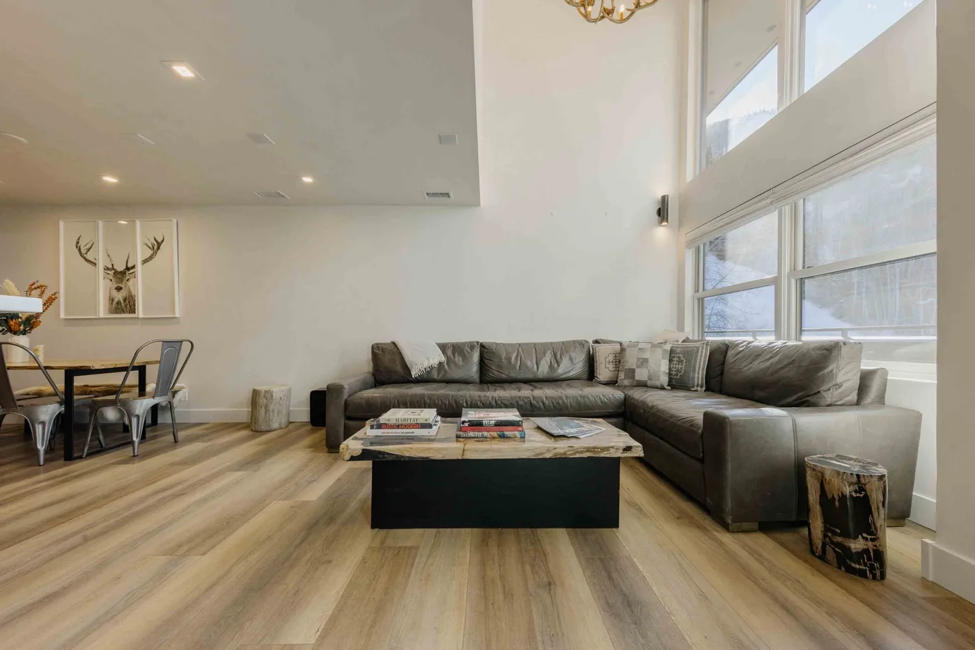 Una sala de estar con asientos seccionales junto a grandes ventanas y una mesa de centro baja.