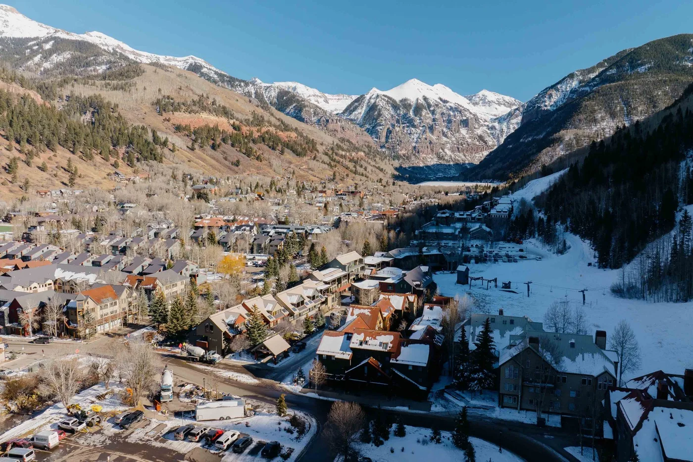 Un pueblo de montaña se extiende por un valle nevado bajo picos escarpados.