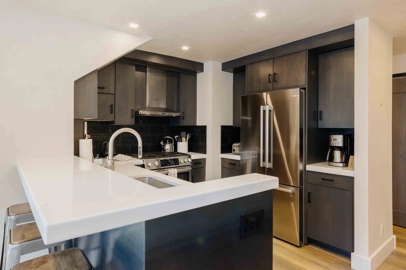 Una cocina moderna con una isla grande, gabinetes oscuros y electrodomésticos de acero inoxidable.