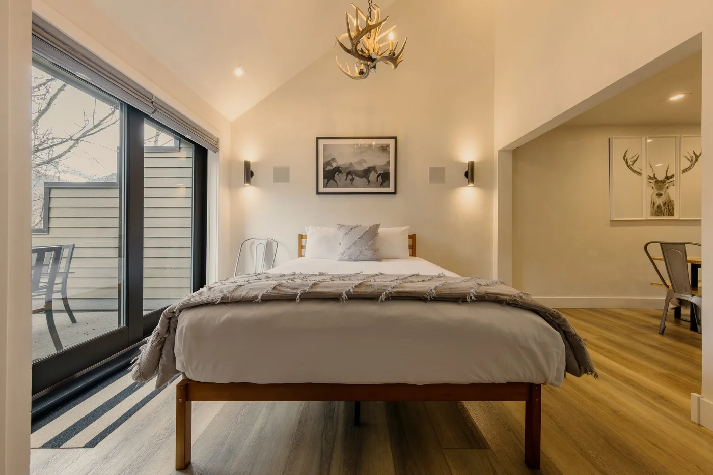 Un dormitorio con una cama bien tendida, arte en la pared y grandes puertas de vidrio.