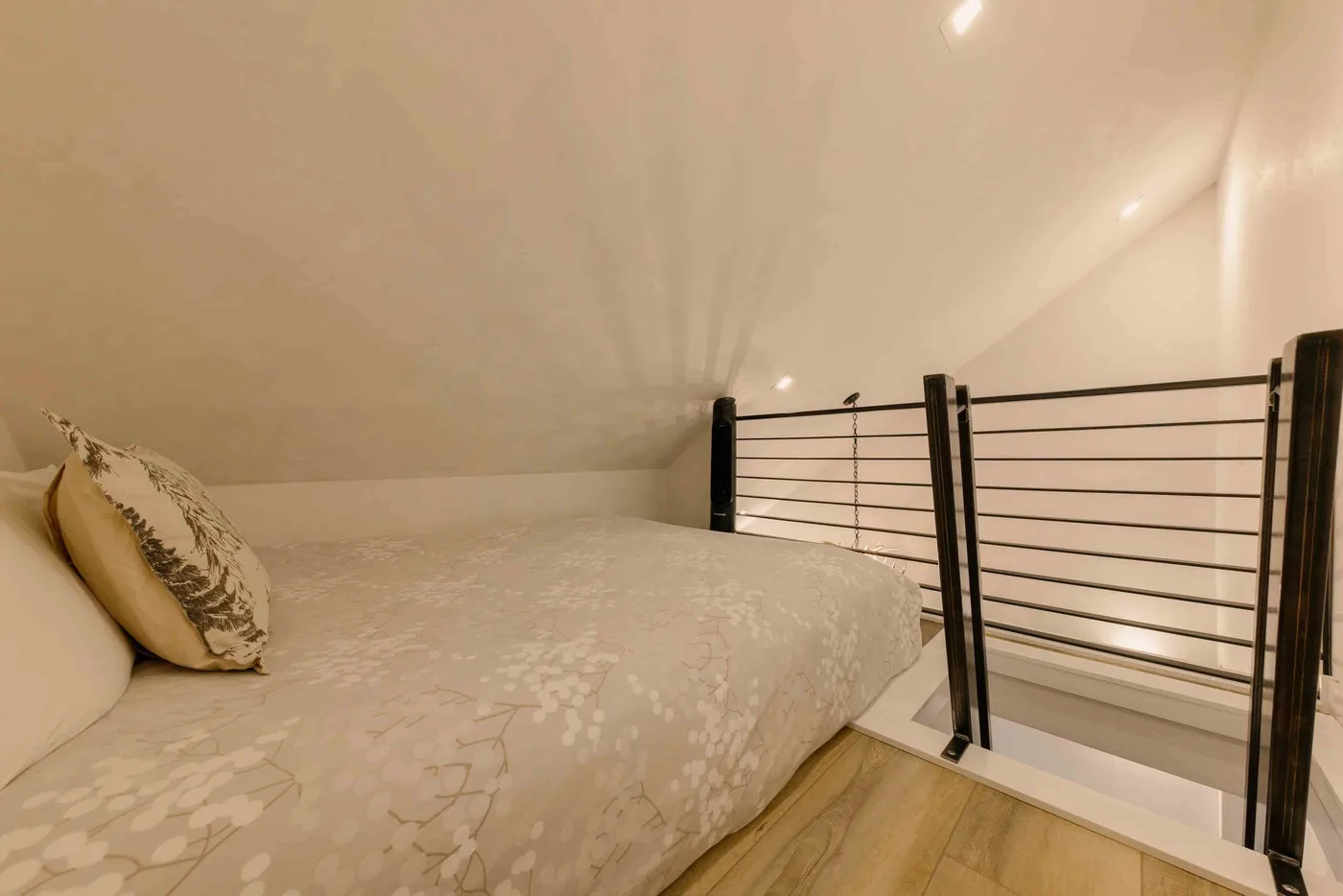 Un dormitorio con una cama junto a una barandilla metálica negra.