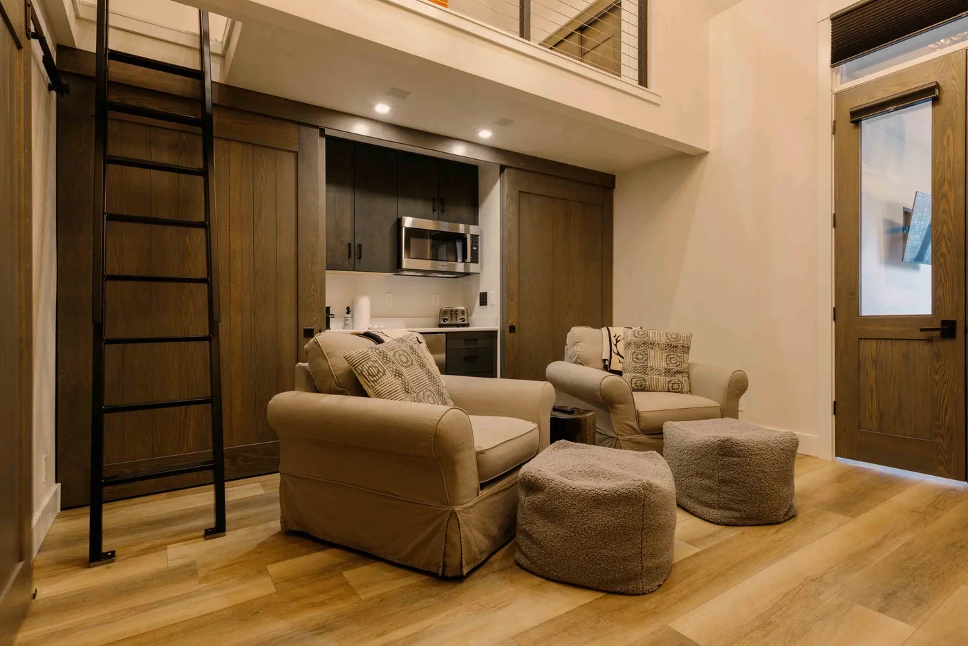 Una sala de estar tipo loft con asientos, una cocina compacta y una escalera al nivel superior.