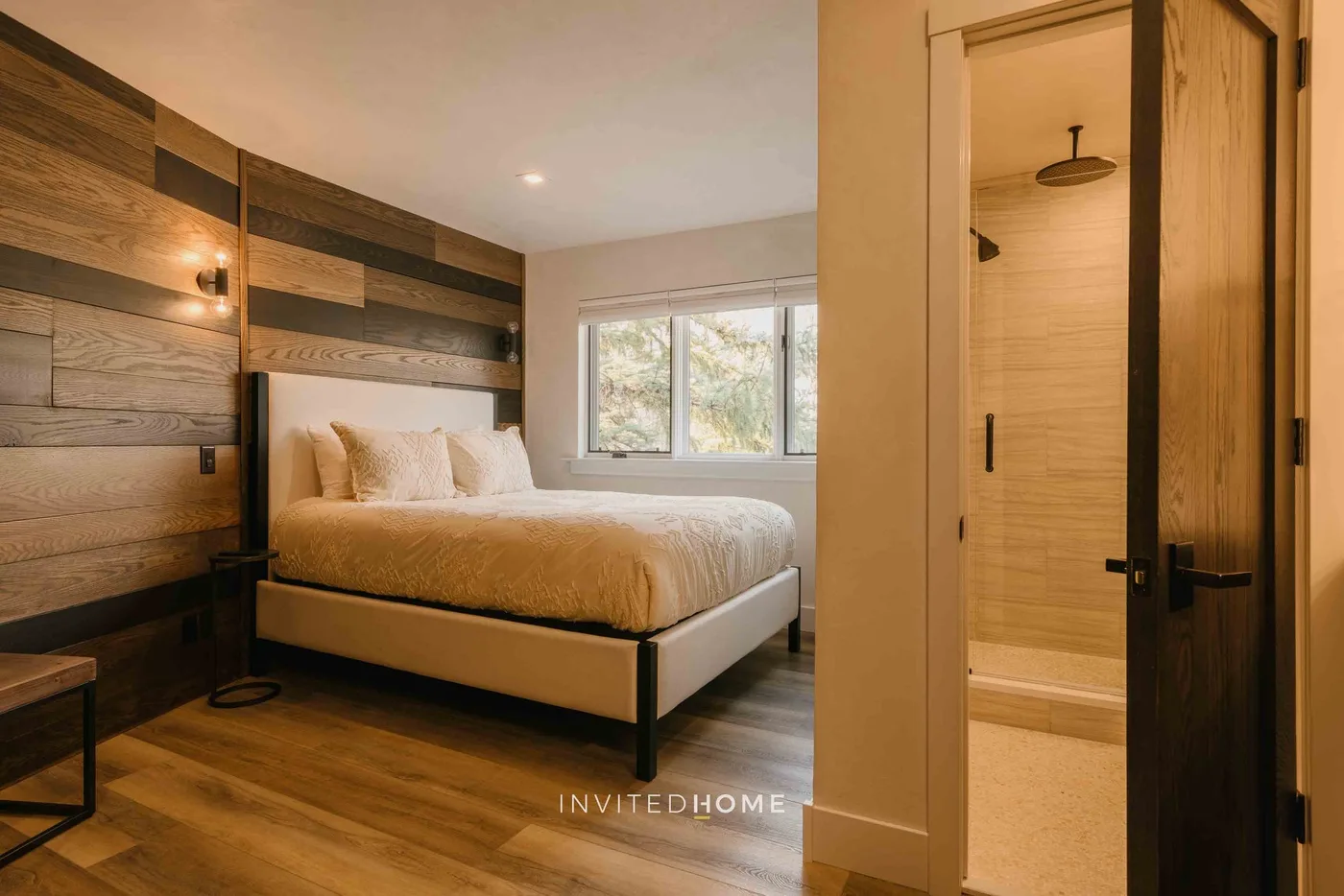 Un dormitorio con una cama y una ventana junto a la entrada abierta del baño.